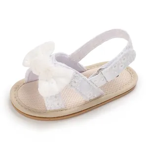 Detail view of white lace baby girl sandal with decorative bow and soft breathable sole