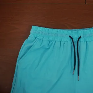 Close-up view of cyan sports shorts featuring an elastic waistband and drawstring