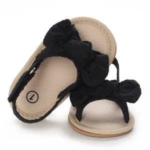 Close-up view of black baby girl sandals featuring a decorative lace bow and soft sole