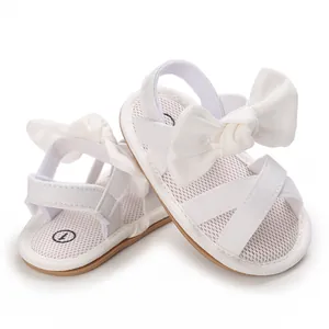 Macro view of white mesh baby sandals featuring a large decorative bow and soft sole