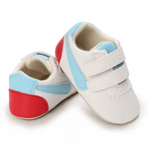 Vista detallada de zapatos blancos para bebés con rayas azules y talón rojo