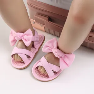 Detail view of pink baby sandals featuring a decorative bow and cross-strap design