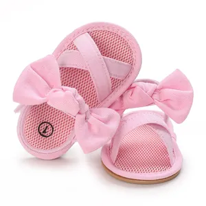 Close-up of pink baby girl sandals featuring a large decorative bow and mesh fabric