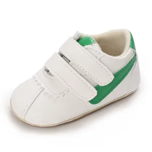 Primer plano de zapato blanco para bebé con raya verde y doble cierre de velcro ajustable.