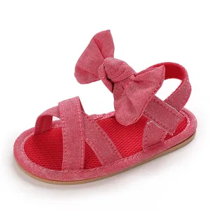 Detail view of red infant walking sandals with a large bow and soft rubber sole