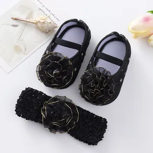 Detail view of black infant flower shoes and matching headband set on a white background