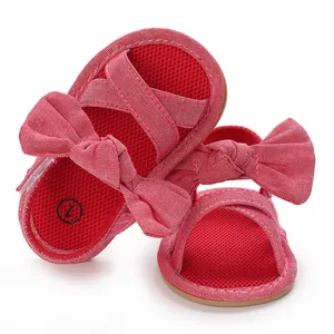 Detail view of red mesh infant girl sandals featuring a large decorative bow and soft sole