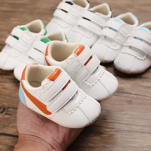 Primer plano de zapatos de bebé blancos con suela blanda y detalles de colores