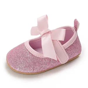Close-up of pink glitter baby girl princess shoes with a satin bow and soft sole.