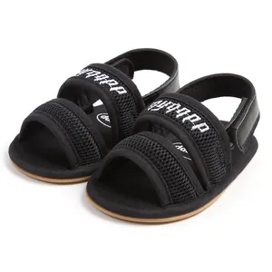 Macro detail view of black breathable mesh infant sandals with soft walking soles.