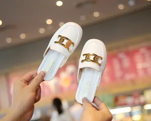 Nahaufnahme von weißen Leder-Mules für Mädchen mit dekorativer goldener Kettenschnalle.