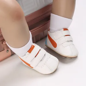 Detalle de los zapatos blancos de bebé con rayas naranjas y suelas blandas para caminar
