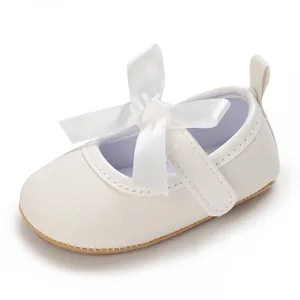Detailed close-up view of a white glitter baby girl shoe with a large satin bow
