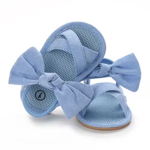 Close-up detail of infant girl summer sandals with a cute blue bow and soft rubber sole