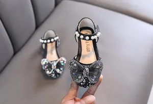 Close-up of girl's black princess shoes with pearl strap and rhinestone butterfly.