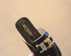 Detailansicht der schwarzen Mädchen-Pantoletten mit Krokodilmuster und Goldschnalle