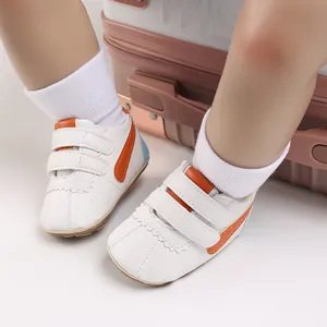Vista detallada de zapatos de bebé blancos con suela blanda y detalles en color naranja