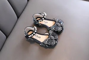Close-up of sparkling black girls' princess shoes with pearls and rhinestones