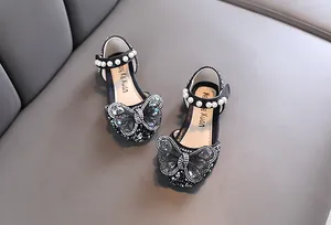 Close-up of black girls' princess shoes with rhinestone butterfly and pearl straps