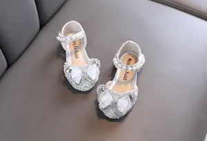Detailed view of silver girls' princess shoes with rhinestone bows and pearls