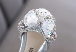 Close-up detail of silver princess shoe featuring sparkling rhinestone bow and gems