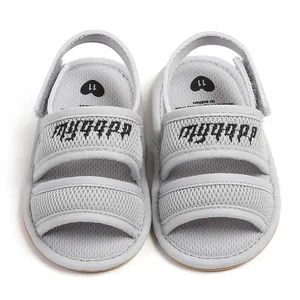Detailed top view of grey mesh baby sandals with embroidered gothic text on straps