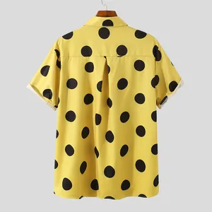 Macro view of yellow men's shirt with bold black polka dots and casual lapel collar.