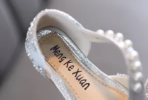 Close-up detail of silver glitter girls' princess shoes with elegant white pearl strap