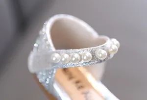 Close-up of pearl strap detail on silver glittery girl's princess dress shoes