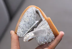 Detailed view of flexible silver glitter girls' princess dance shoes with pearl accents.