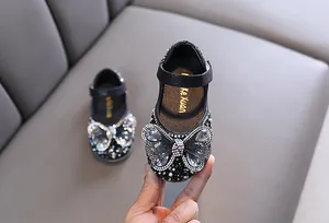 Detalle de zapatos de princesa negros para niña con un gran lazo de mariposa de strass