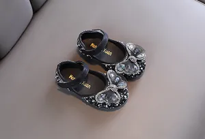 Zapatos de princesa negros para niñas con una gran mariposa de pedrería brillante.