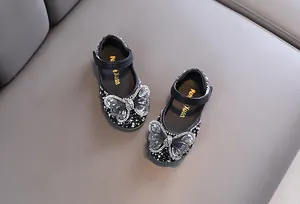 Vista detallada de zapatos negros para niña con lazos de mariposa en diamantes