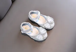 Vista detallada de zapatos de princesa plateados para niña con pedrería y lazo