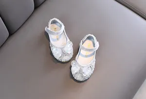 Vista detallada de zapatos de princesa plateados para niña con pedrería y lazos de malla.