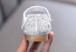 Primer plano de adornos de perlas y pedrería en zapatos de princesa plateados