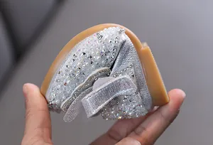 Vista detallada de la suela flexible en zapatos de princesa plateados con pedrería