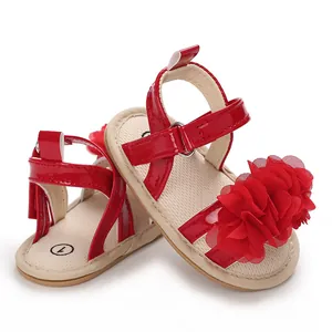 Gros plan de sandales rouges pour bébé fille avec grande fleur en tissu et scratch