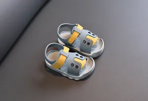 Close-up of grey and yellow soft-sole baby sandals with hook-and-loop strap