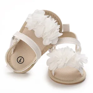 Détail de sandales blanches pour bébés filles avec grandes fleurs en mousseline