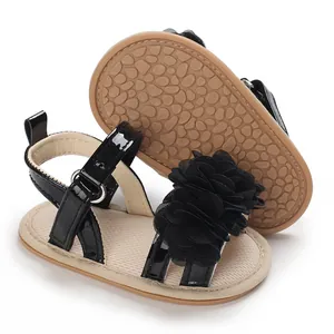 Détail de sandales noires pour bébé avec fleur décorative et semelle en caoutchouc antidérapante