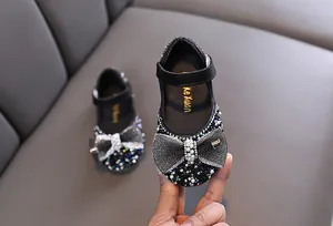Primer plano de zapatos Mary Jane negros para niña con pedrería y lazo de perlas