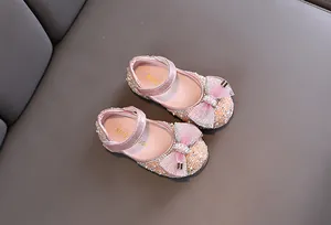 Detalle de zapatos de princesa rosas para niñas con purpurina, perlas y lazo elegante