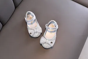Detalle de zapatos de princesa plateados brillantes para niñas con un lazo elegante