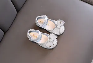 Detalle de zapatos Mary Jane plateados para niña con lazo de malla y perlas brillantes.