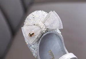 Primer plano de zapato de princesa plateado para niña con detalle de lazo de perlas y cristal