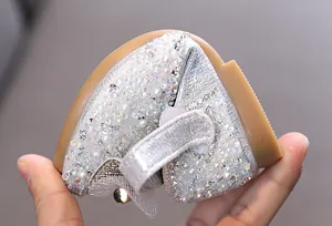 Primer plano detallado de zapatos de princesa plateados para niñas con perlas y pedrería