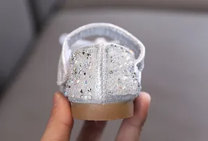Primer plano de pedrería y perlas en el talón de los zapatos plateados de princesa para niña.