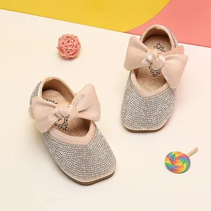 Detail view of sparkling rhinestone baby girl princess shoes with large satin bows.