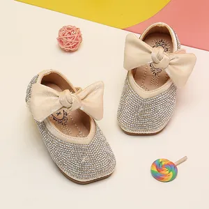 Detailed view of sparkling rhinestone baby girl princess shoes with large cream bows
